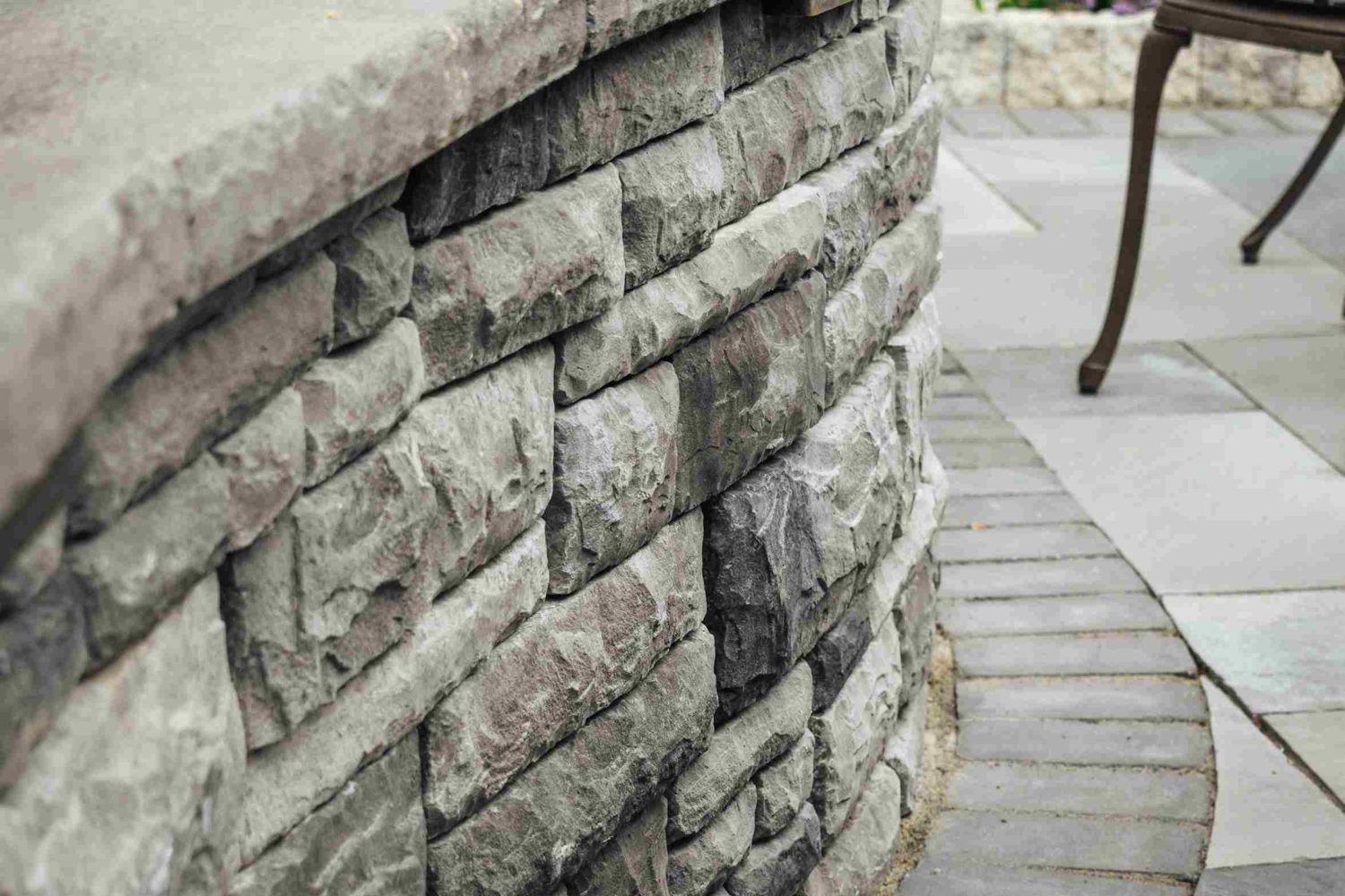 Curved stone wall detail with bluestone patio