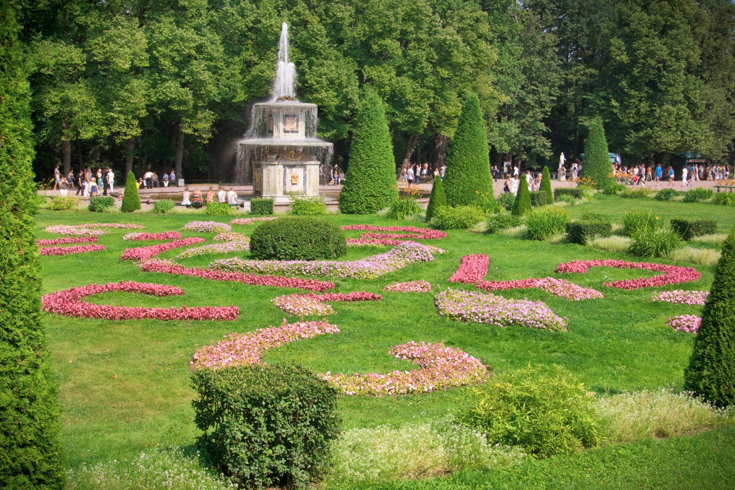 Bright sunny day. blooming flower beds, a fountain and green bushes. place for rest and walking