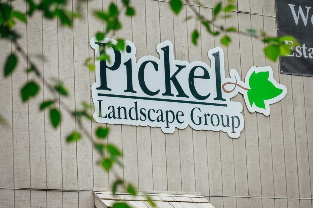Pickel Landscape Group logo sign on building exterior surrounded by greenery