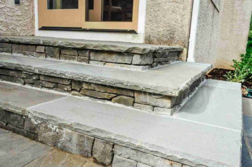 Natural stone entry steps made of bluestone and stacked stone veneer.